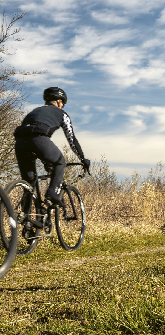 A woman riding a bike on a path near a lake. Description generated by AI