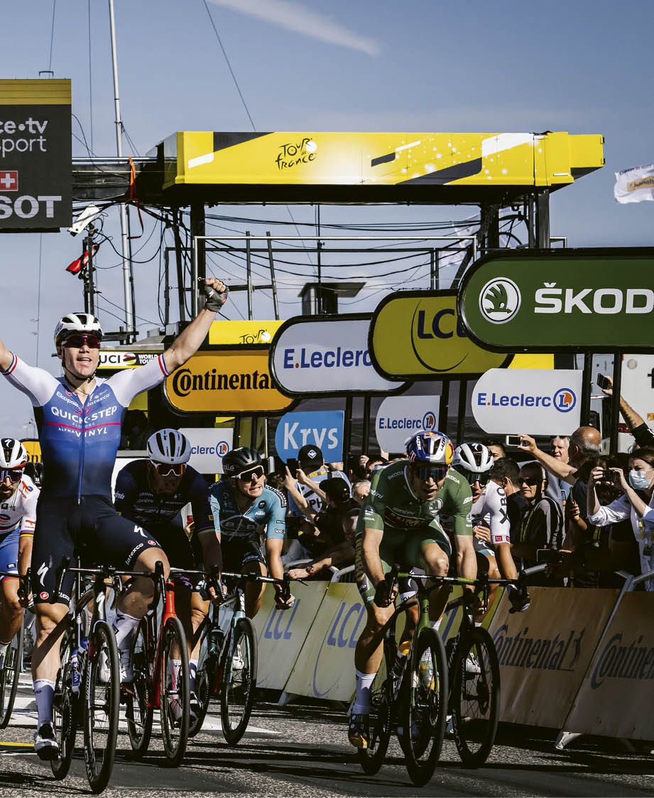 A man wearing a blue shirt and white shorts is crossing the finish line. Description generated by AI